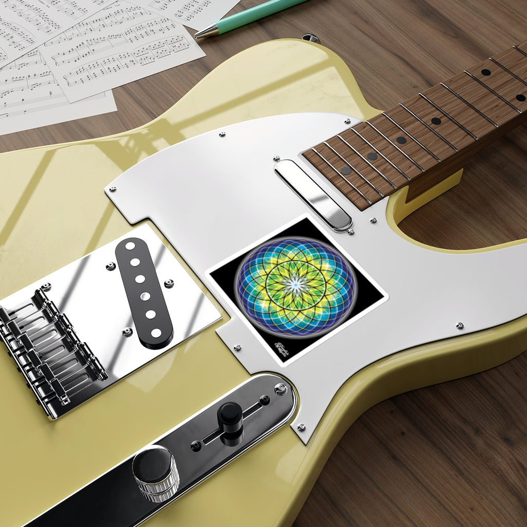 Close-up of a guitar body with a colorful mandala decal on a wooden surface.