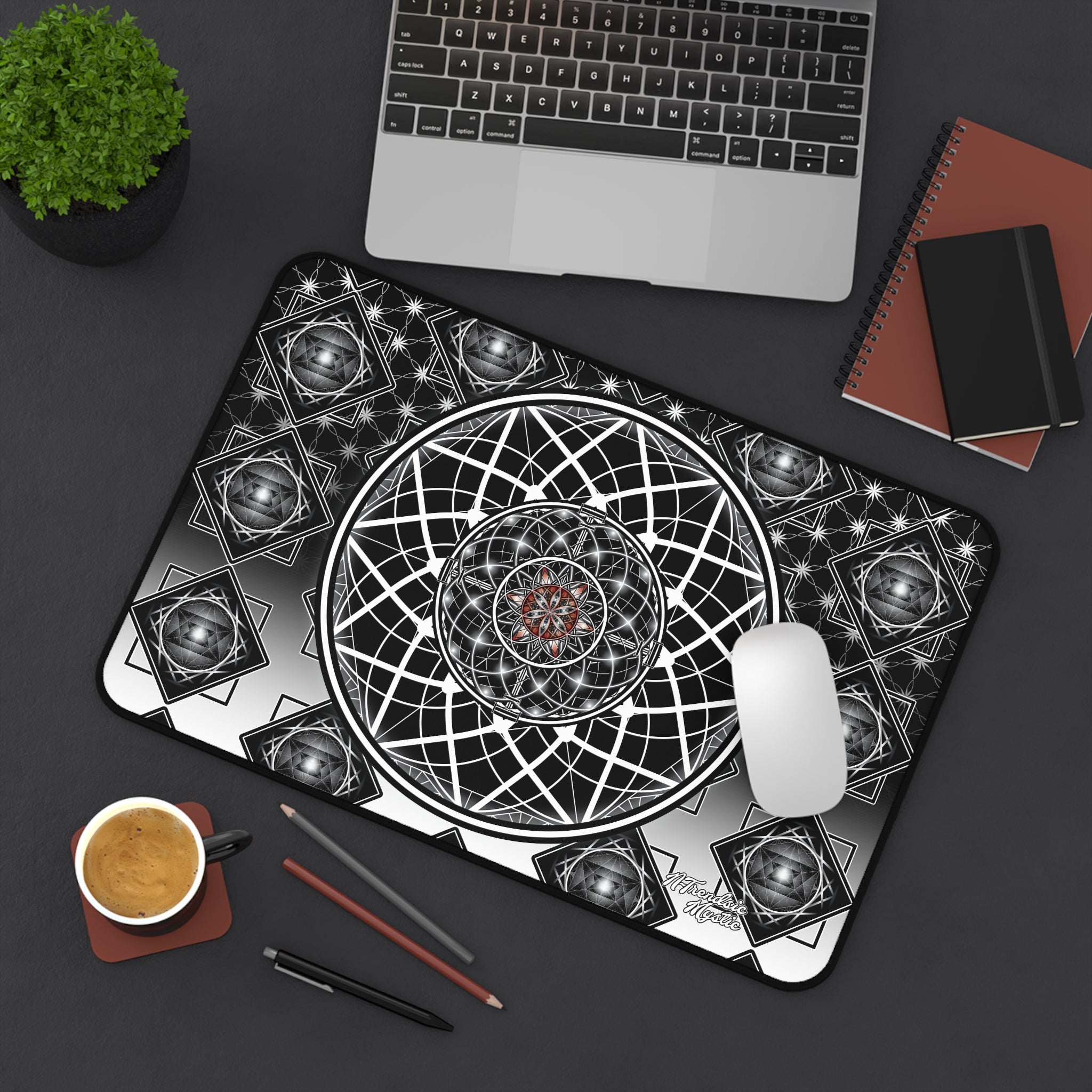 Mouse pad with geometric design on a desk with laptop, notebook, and coffee.