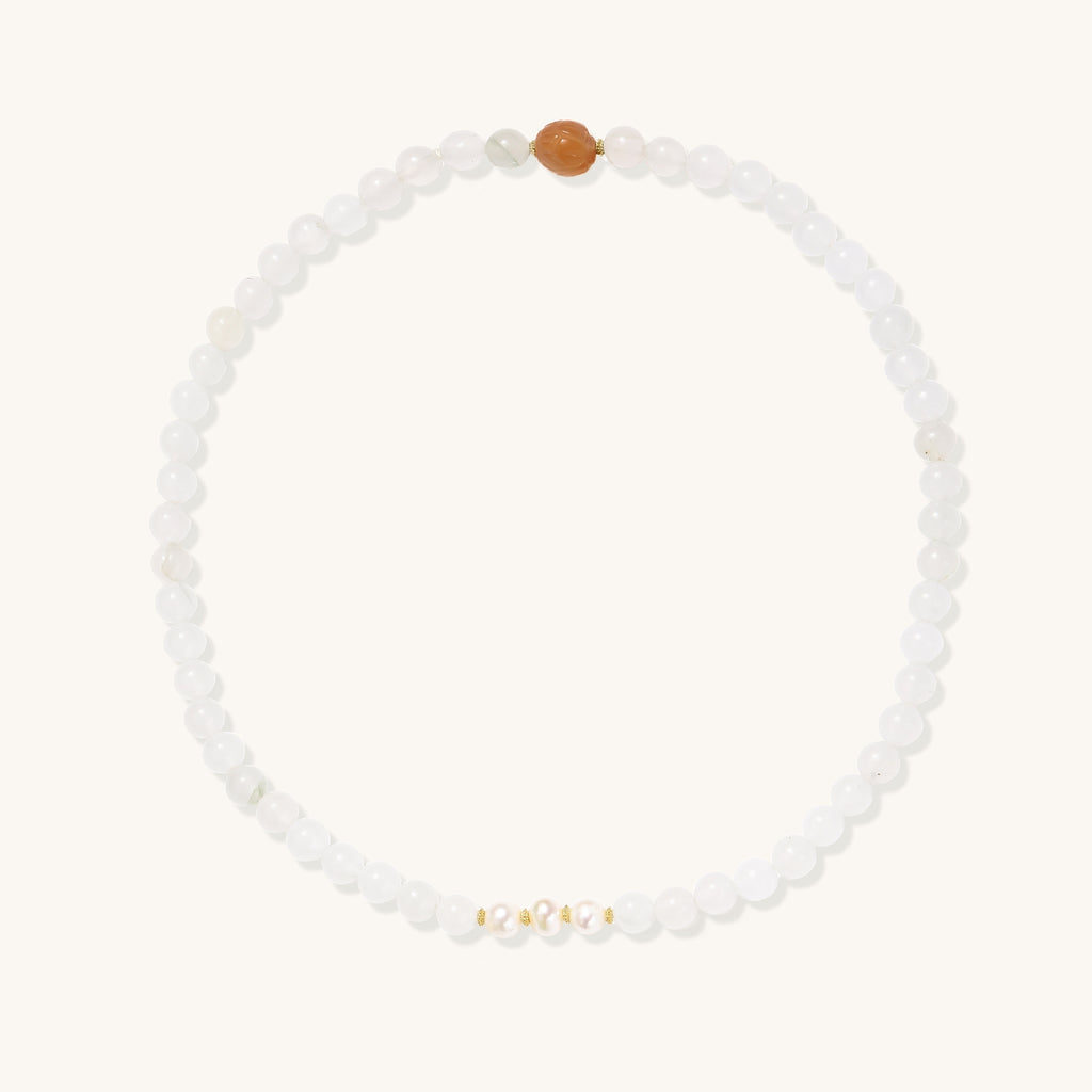 Stretch bracelet with white jade beads, freshwater pearls, and orange agate centerpiece on cream background.
