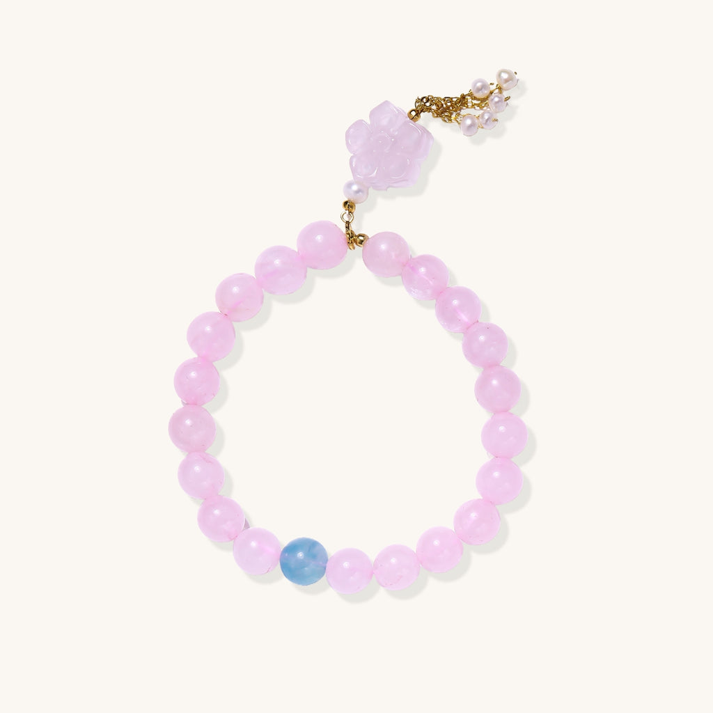 Beaded bracelet with pink rose quartz stones, blue aquamarine accent, and pearl chain details on white background