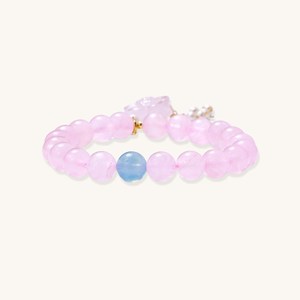 Beaded bracelet with pink rose quartz stones, blue aquamarine accent, and pearl chain details on white background