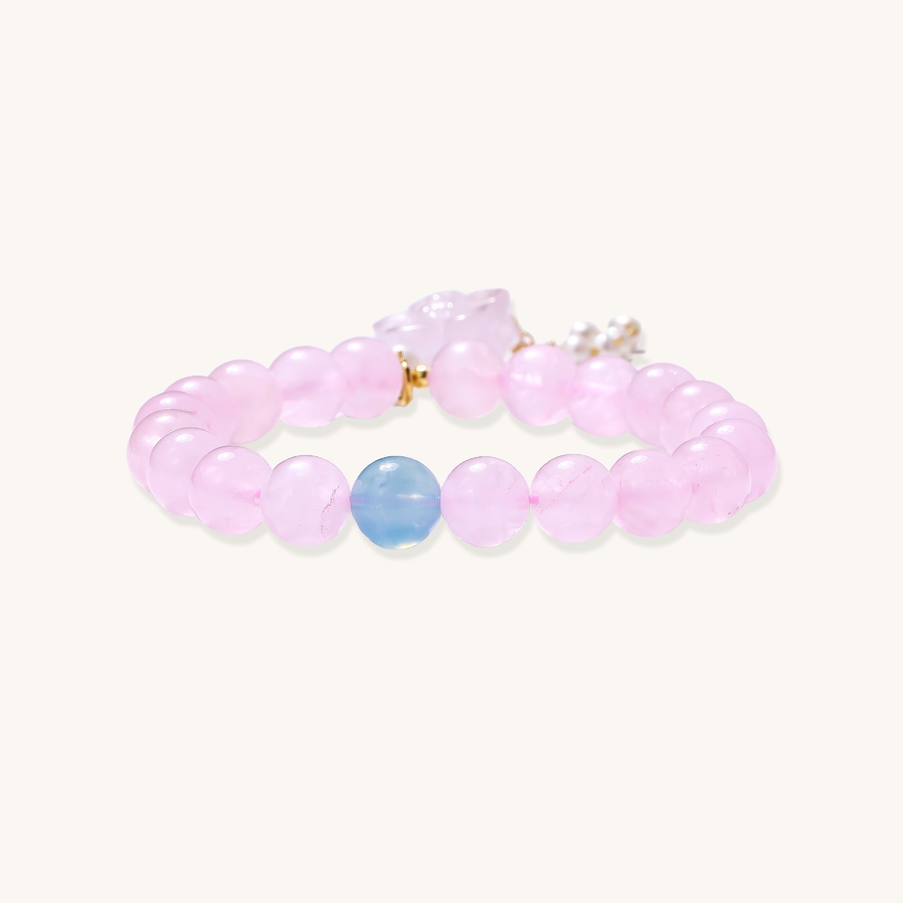 Beaded bracelet with pink rose quartz stones, blue aquamarine accent, and pearl chain details on white background