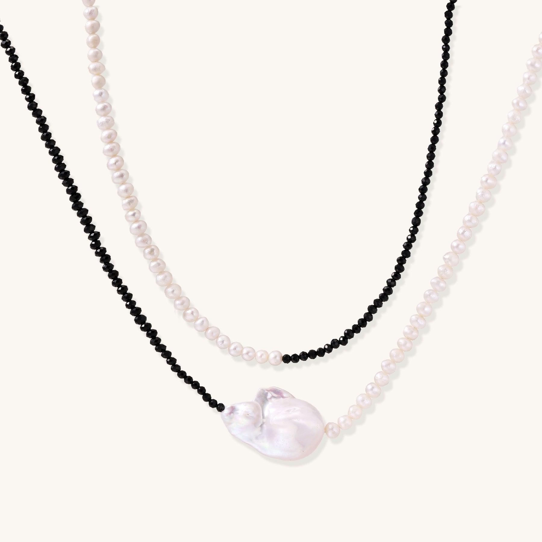 Two-strand necklace with black crystal beads and white pearls featuring a large baroque pearl centerpiece on white background.