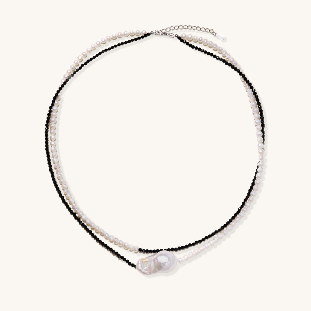 Two-strand necklace with black crystal beads and white pearls featuring a large baroque pearl centerpiece on white background.