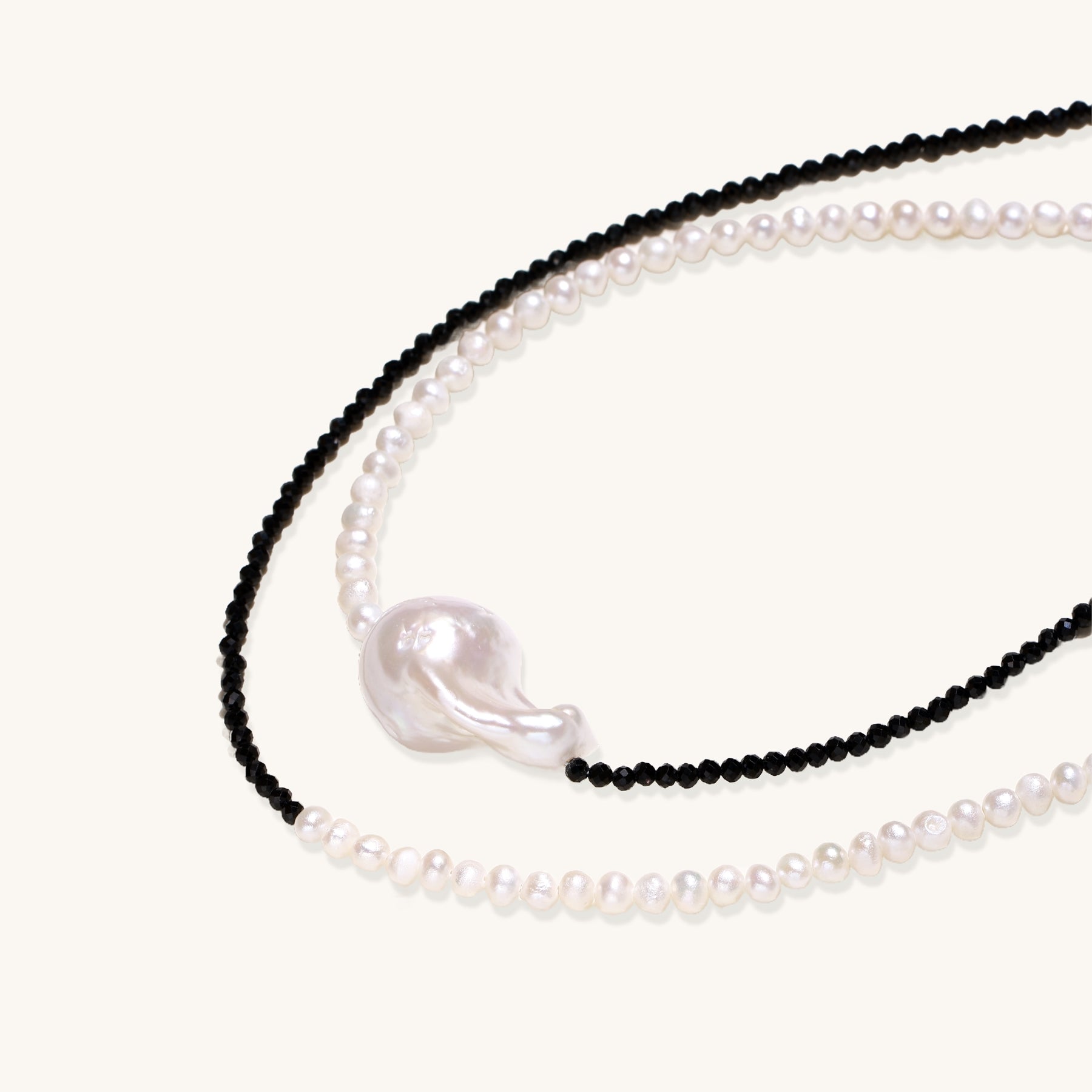 Two-strand necklace with black crystal beads and white pearls featuring a large baroque pearl centerpiece on white background.