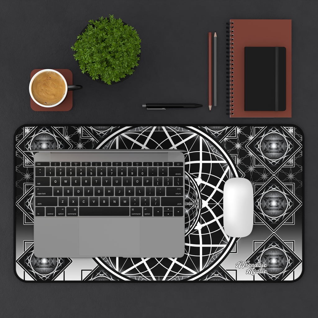 Desk setup with a laptop, mouse, and stationery items on a black surface with a geometric patterned mat.