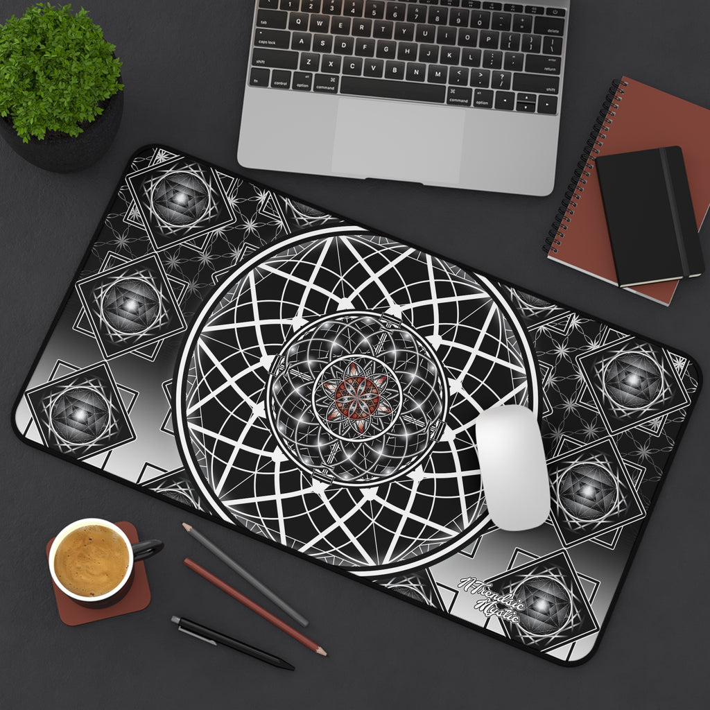 Desk setup with a geometric design mouse pad, laptop, notebook, and coffee cup.