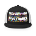 Black and white trucker cap with colorful mandala background and bold text reading In Everything Give Thanks.