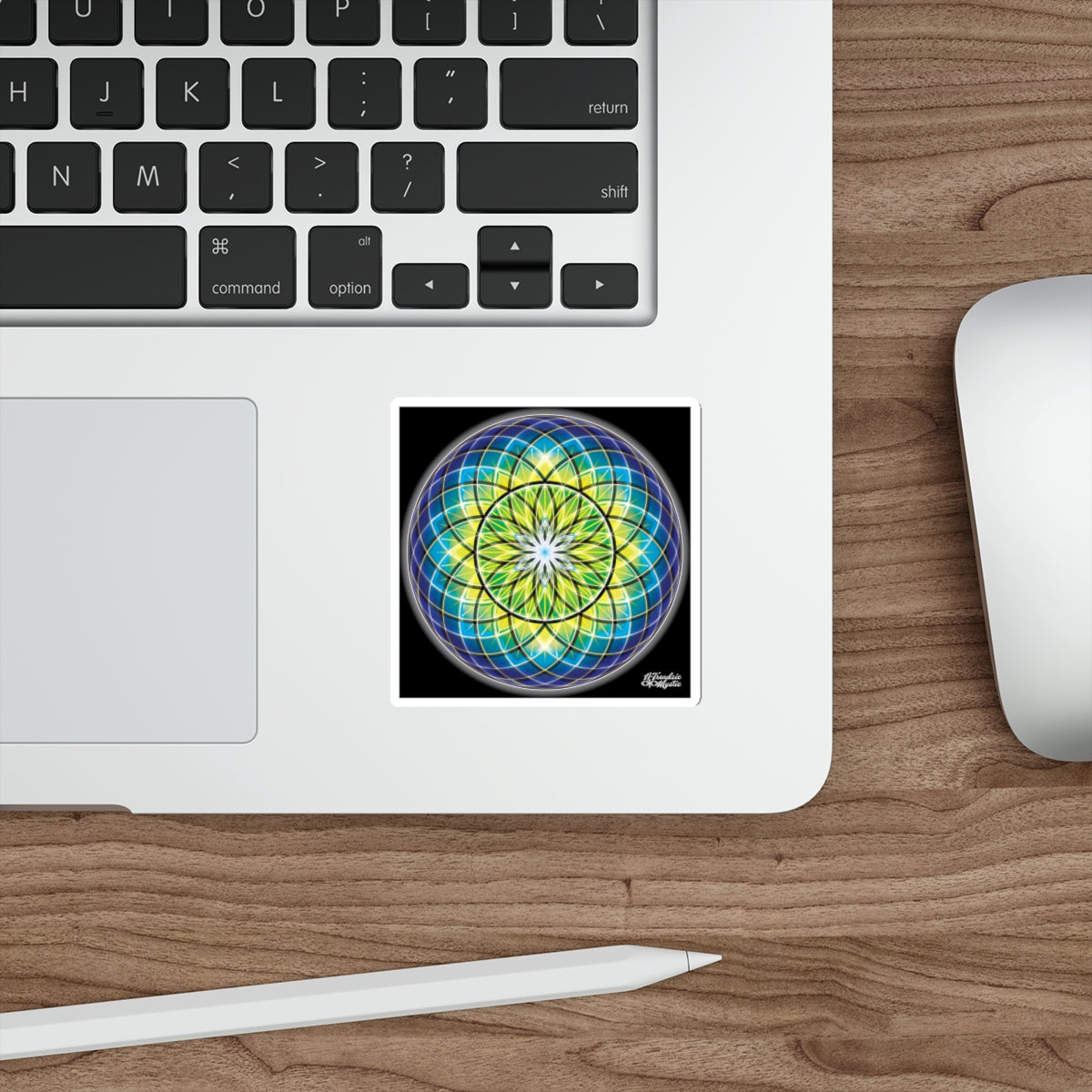 Colorful mandala sticker on a laptop with keyboard, mouse, and stylus on a wooden desk.