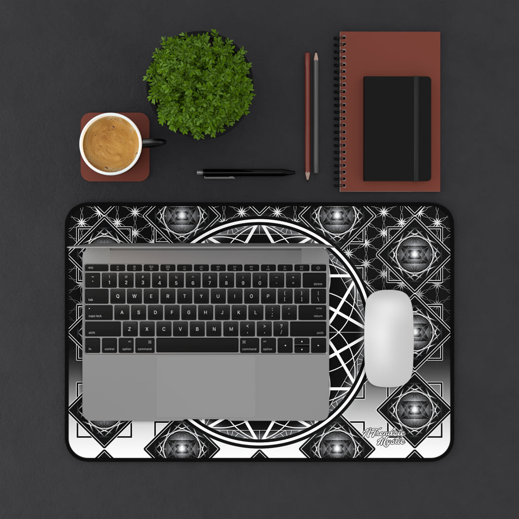 Laptop on a decorative black and white mat with a cup, plant, and stationery items on a dark surface