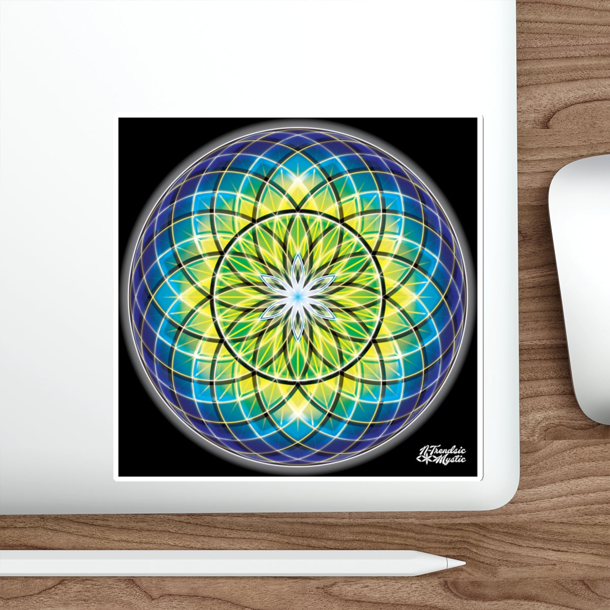 Colorful mandala design on a laptop screen with a white mouse and pen on a wooden surface.
