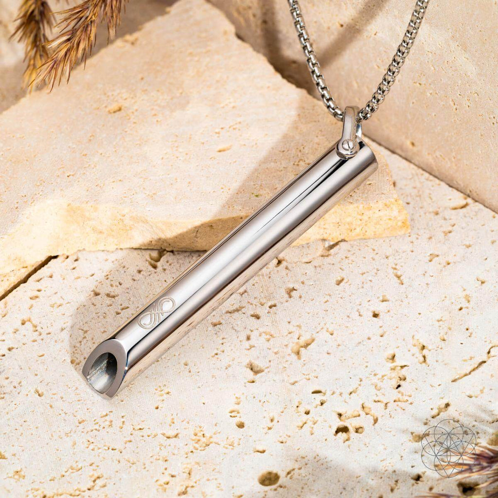 Silver pendant necklace on a textured beige surface