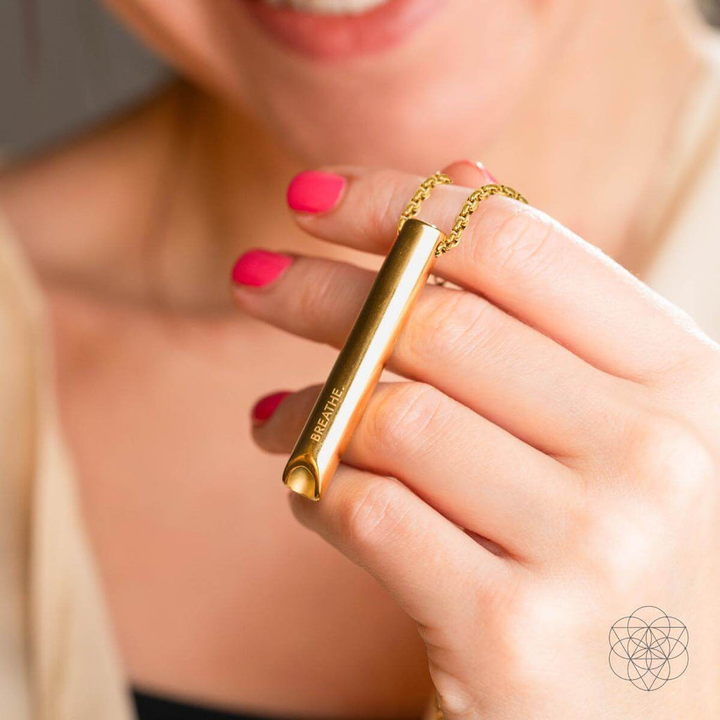 Gold cylindrical product with 'BareMinerals' branding held by a person with pink nail polish.