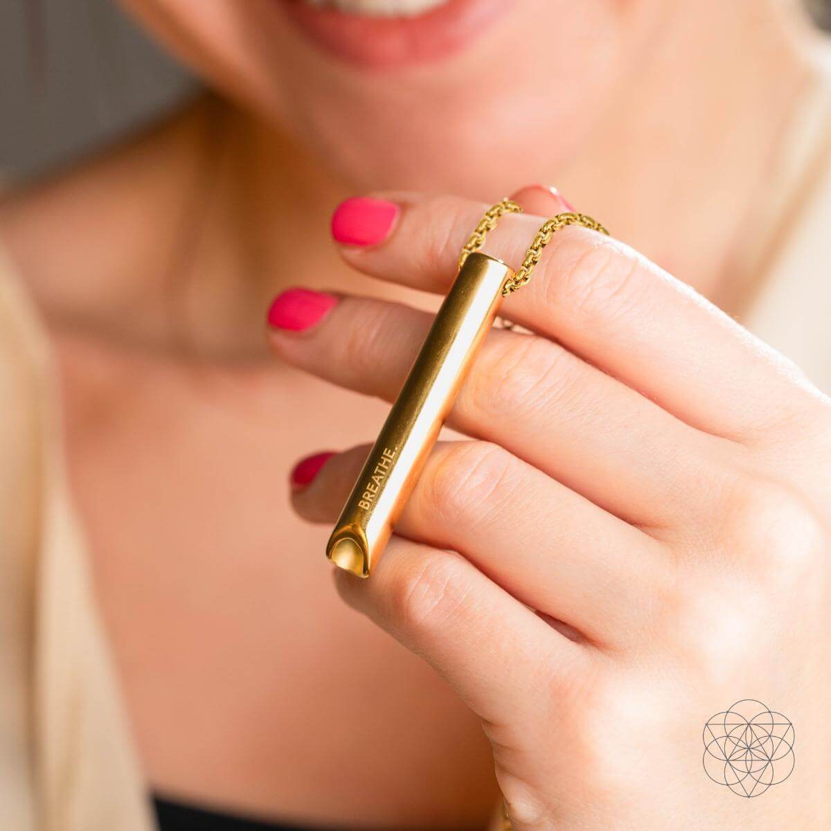 Gold cylindrical product with 'BareMinerals' branding held by a person with pink nail polish.
