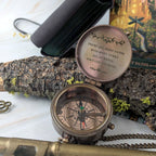 Bronze compass with engraved text on a natural background
