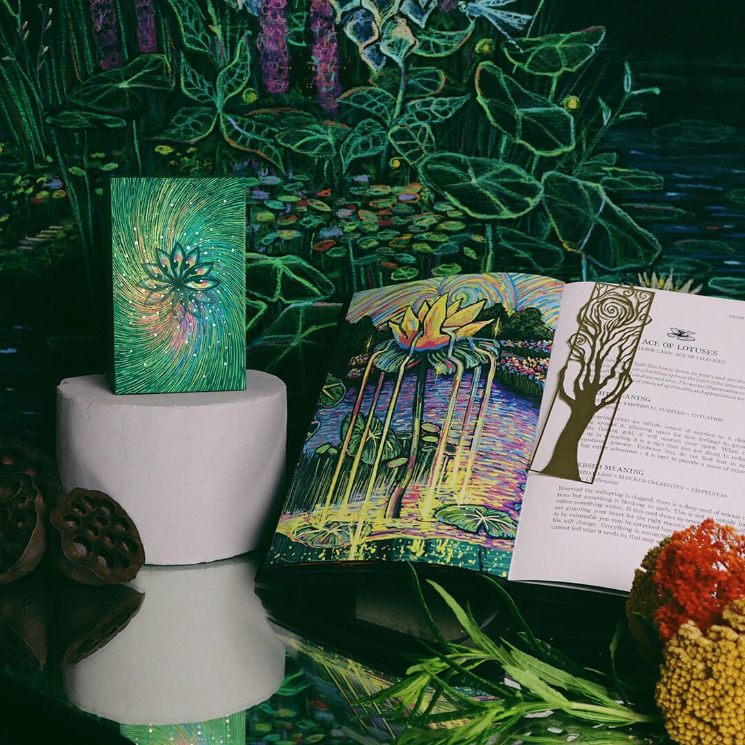 Artistic display with books, a small painting, and decorative elements on a reflective surface.