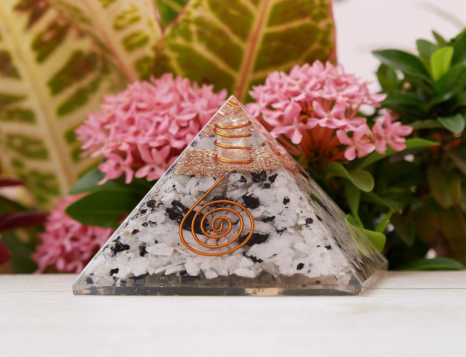 Handcrafted gemstone orgone pyramid with copper coil design, available in multiple decorative variations.