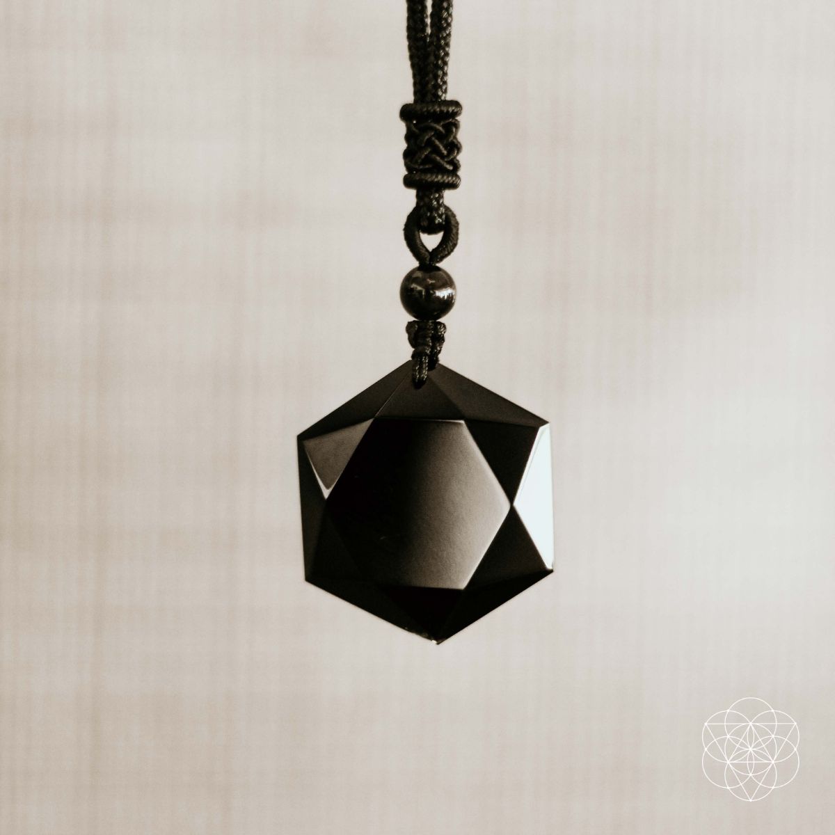 Black geometric pendant on a beige background