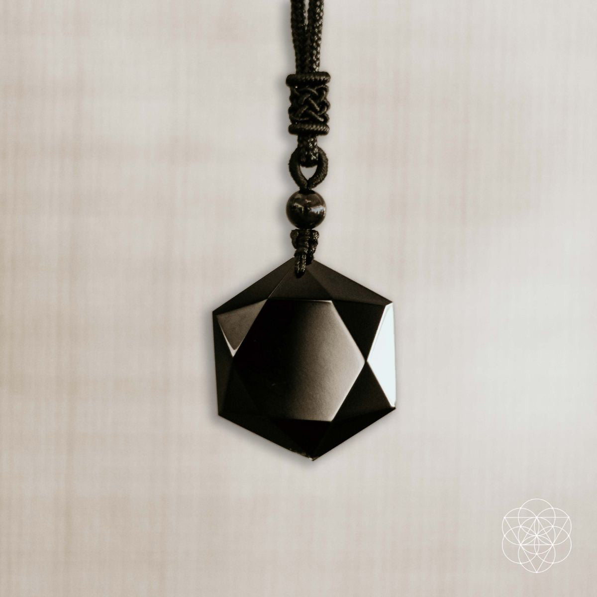 Black geometric pendant on a beige background