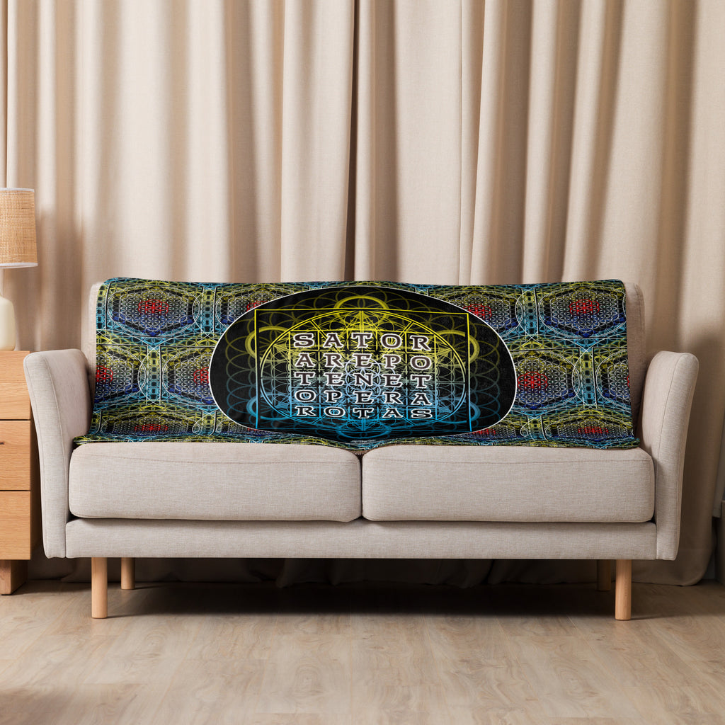 Sofa with a decorative blanket featuring geometric patterns and text in a living room setting.