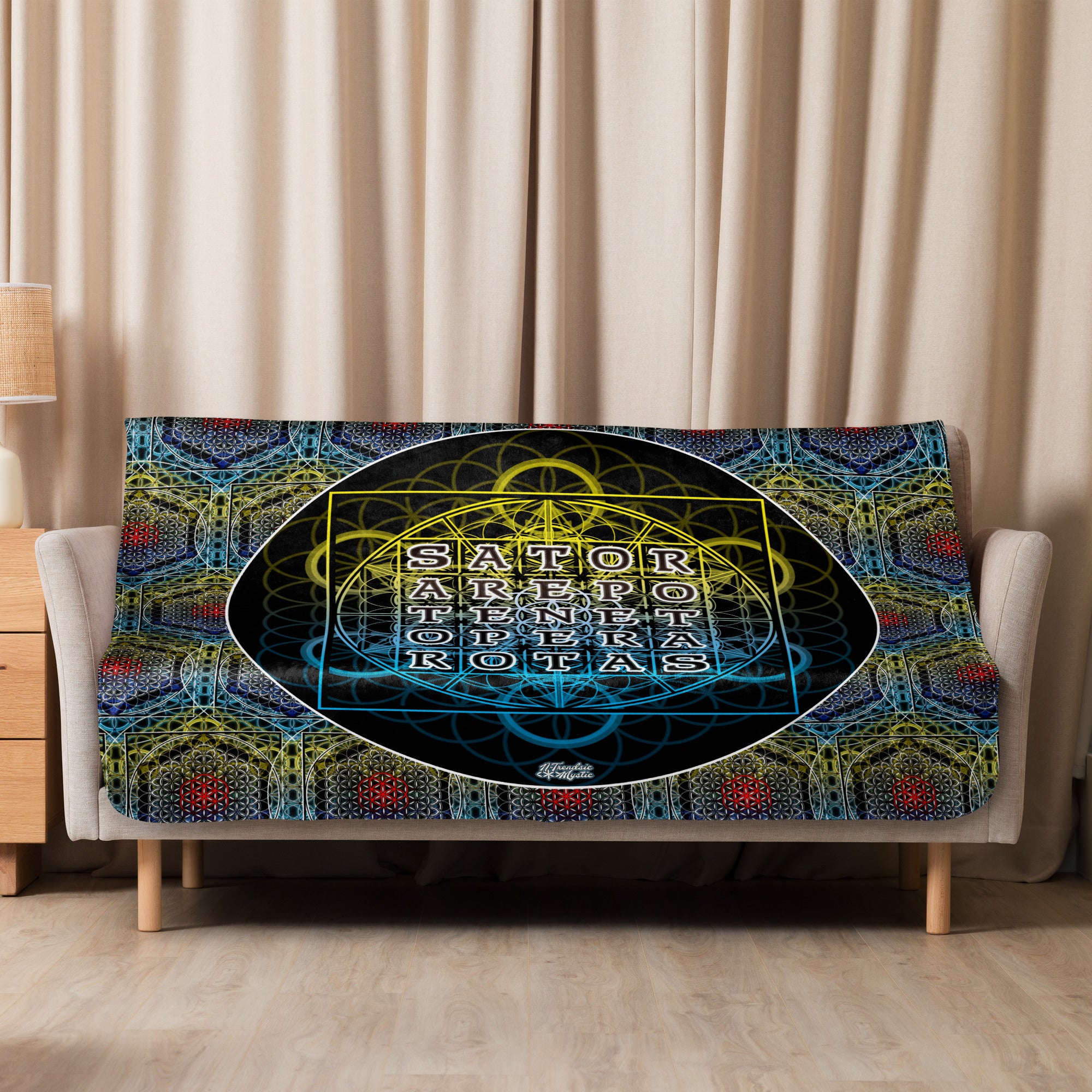 Decorative blanket with geometric design and text on a bed in a room with beige curtains.