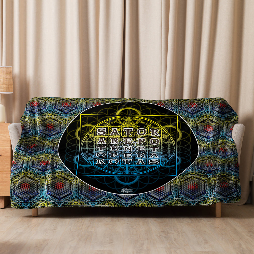 Decorative blanket with geometric pattern and 'Sator' text on a couch against a beige curtain background.