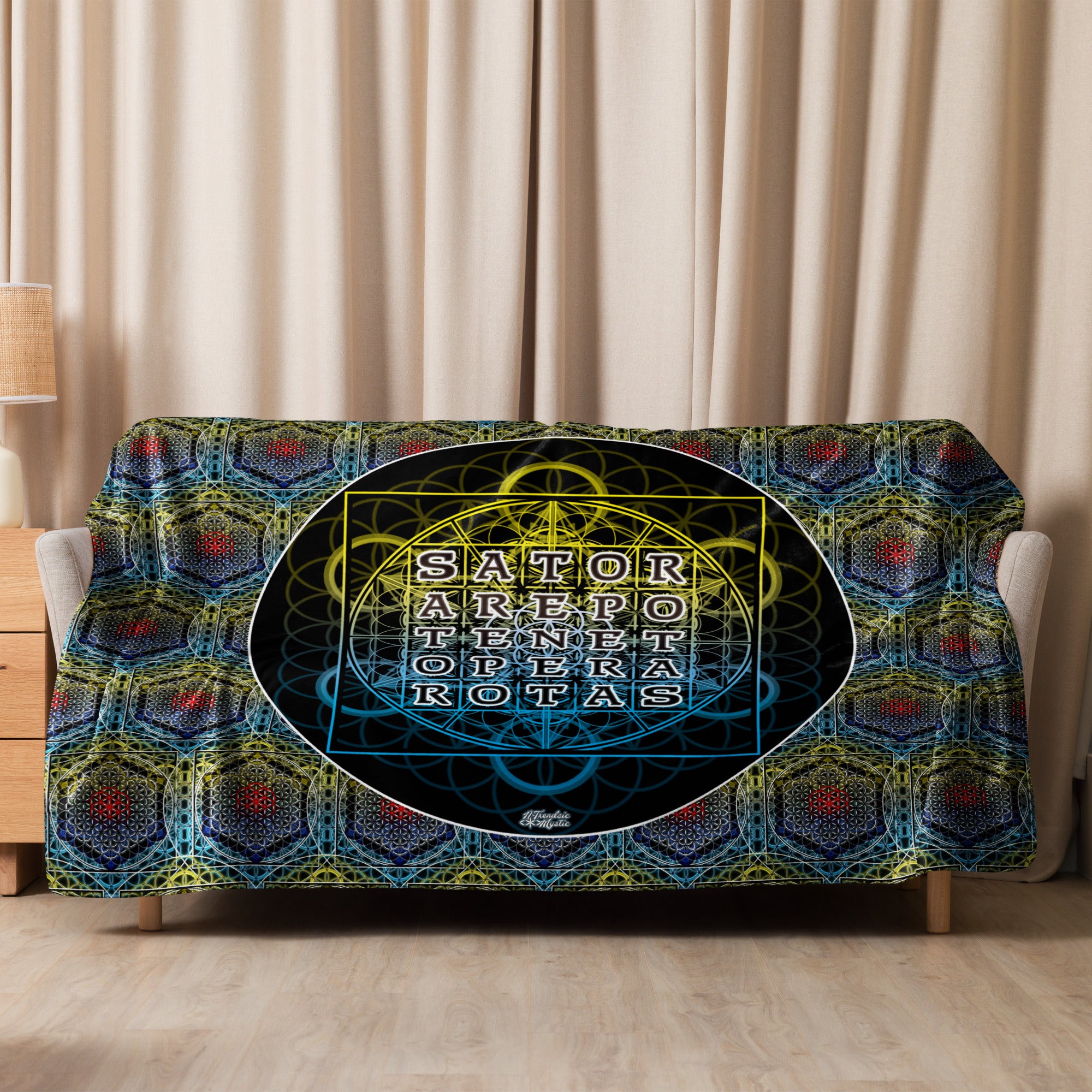 Decorative blanket with geometric pattern and 'Sator' text on a couch against a beige curtain background.